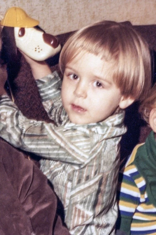 Andrew Amato as a young child holding a toy dog.